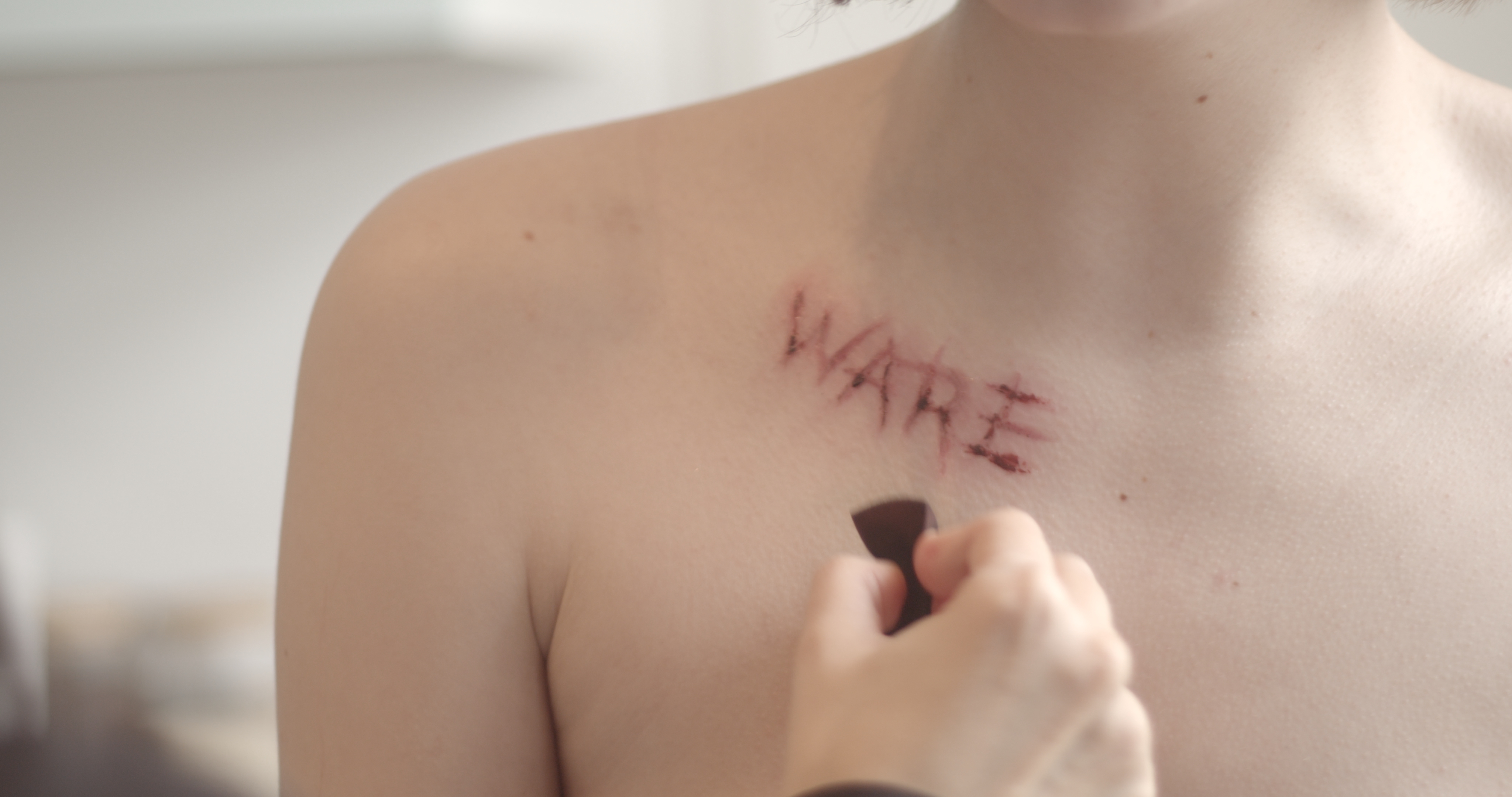 Still from a Making-Of video of a photoshooting depicting 'ware' meaning product written on female bodies. by f-land